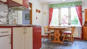 A kitchen with a dining table and chairs, a window with curtains, and a radiator under the window.