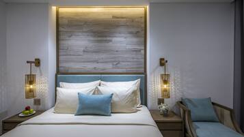 A modern bedroom with a wooden headboard, a bed with white and blue bedding, two bedside tables with lamps, and a small side table with a vase.
