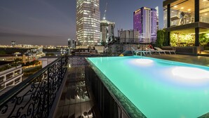 Una piscina en la azotea con vistas a edificios de la ciudad de noche.