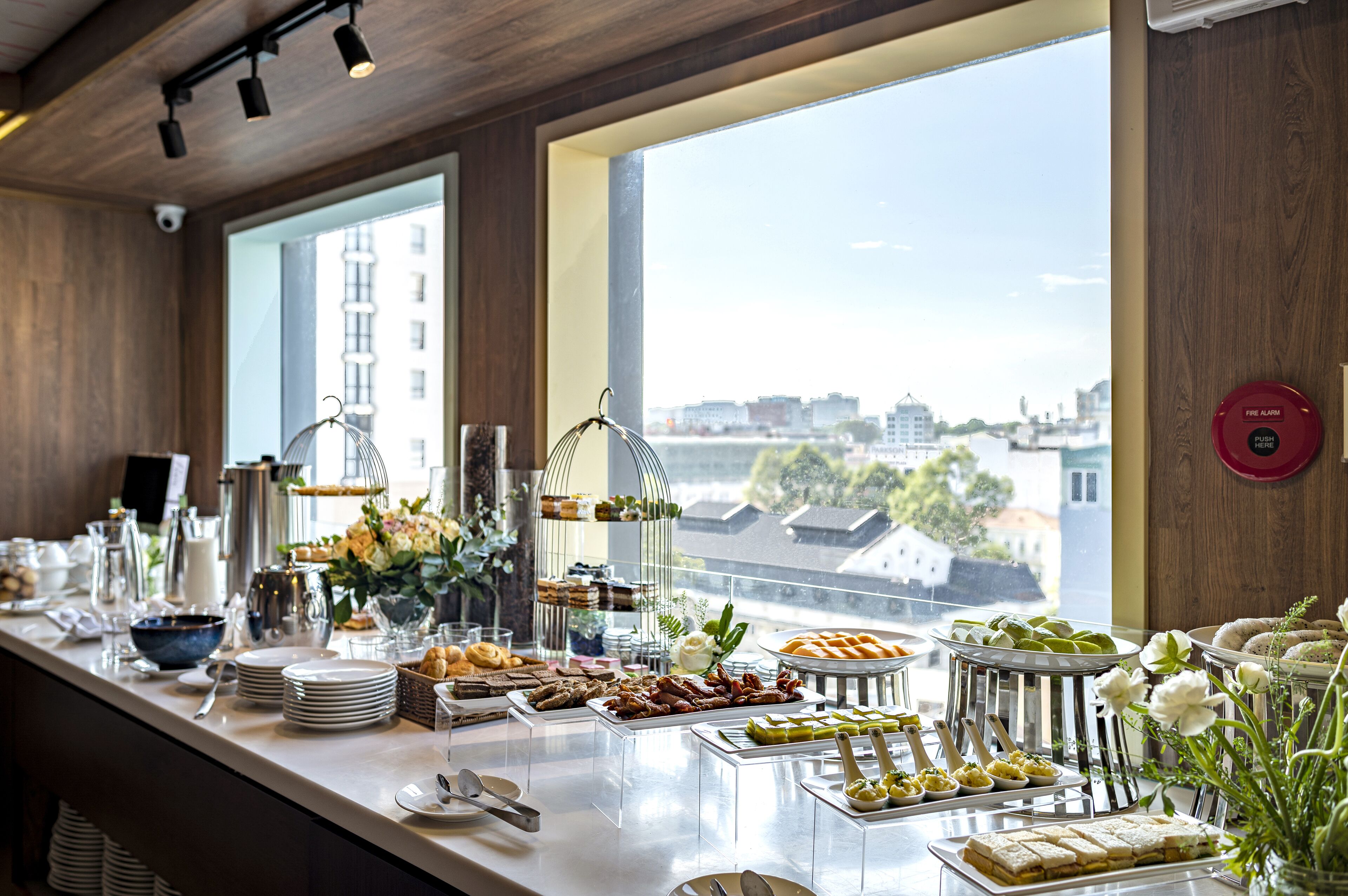A buffet with various food items and a view of the city through large windows.