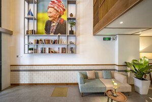 Eine moderne Lobby mit einer großen Bücherwand, einem Sofa, einem Couchtisch und einer Topfpflanze.