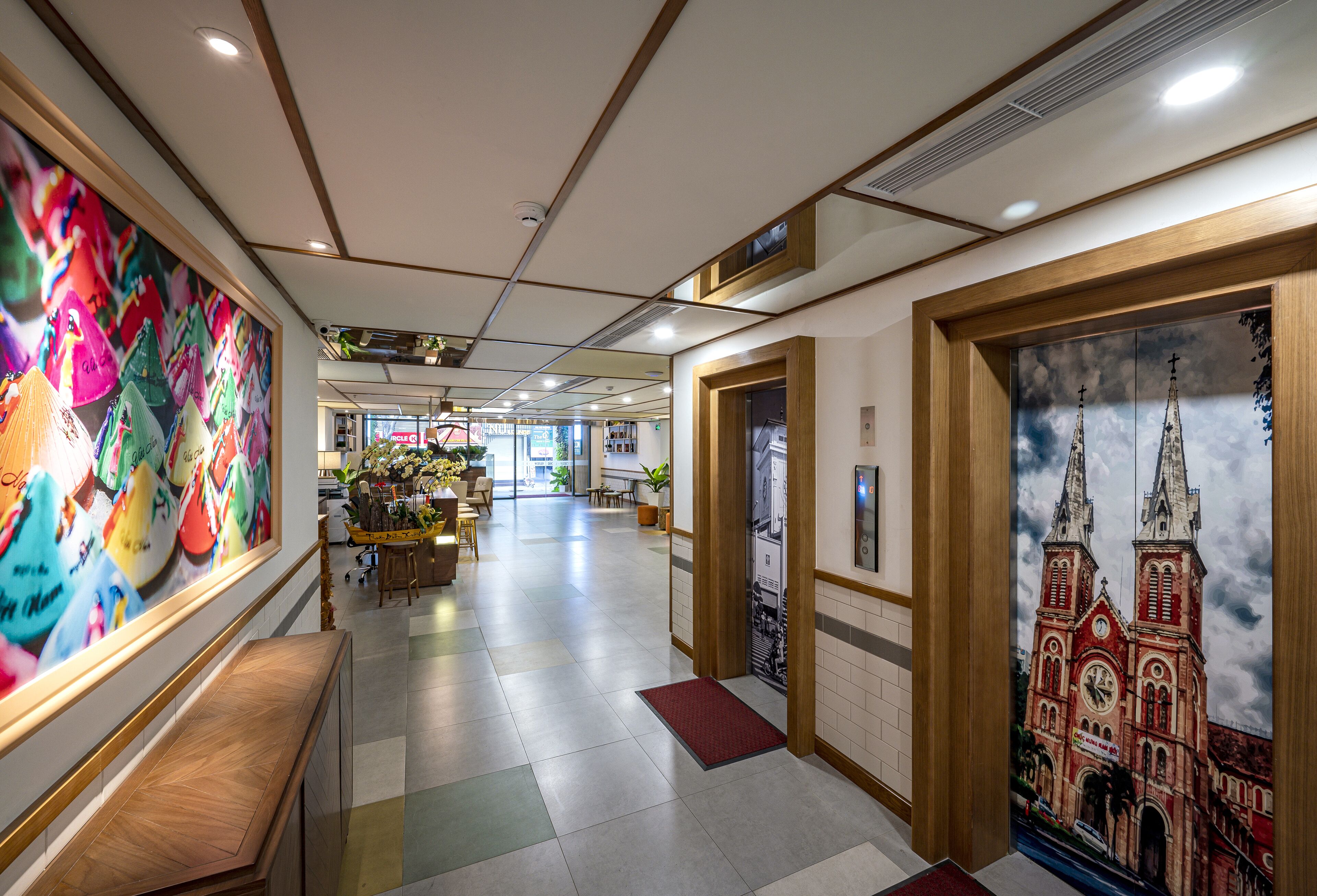 A hotel lobby with a colorful mural, a reception desk, a seating area, and a large window with a view of a building.