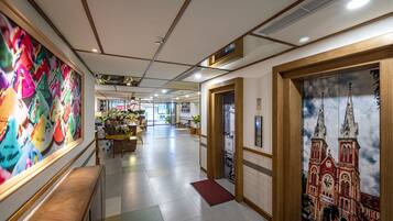 A hotel lobby with a colorful mural, a reception desk, a seating area, and a large window with a view of a building.