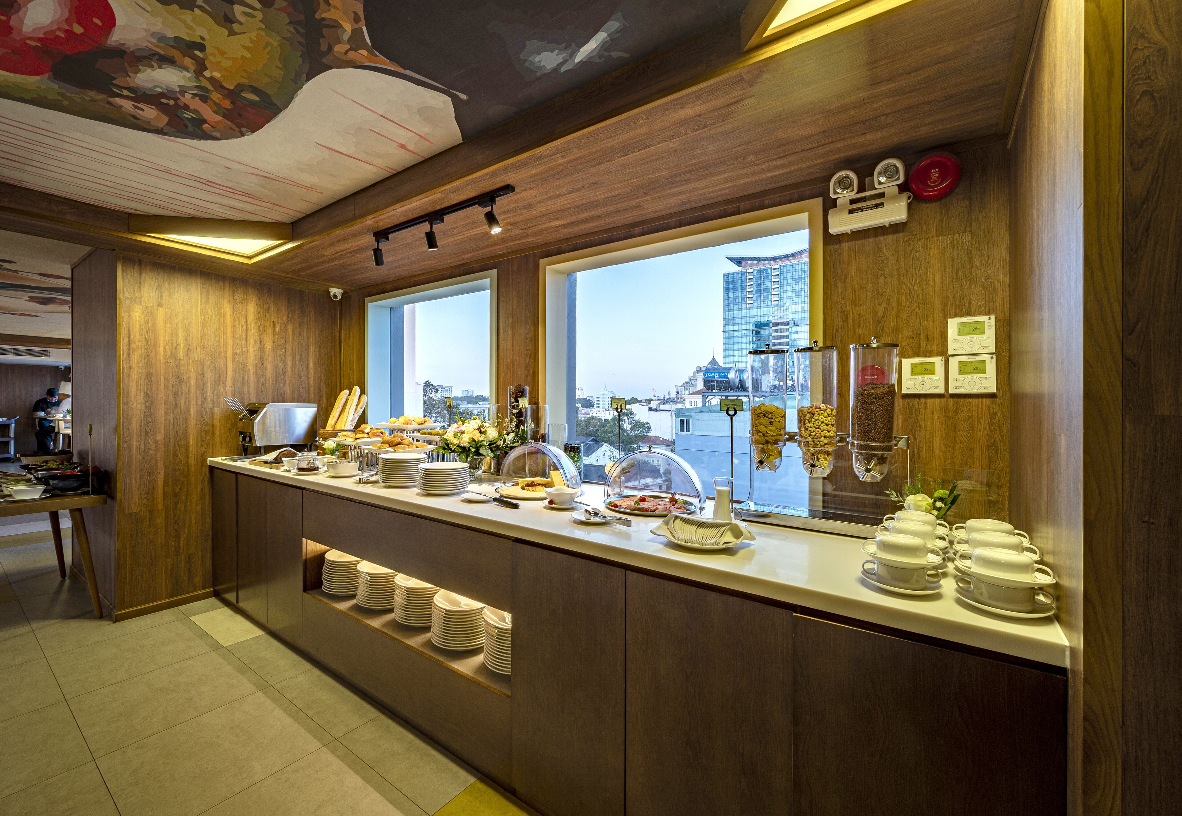 A buffet counter with a view of a city skyline, wooden paneling, and a variety of food items.
