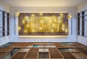 Un interior moderno con piso de listones de madera, una lámpara de pared y un ventanal grande.