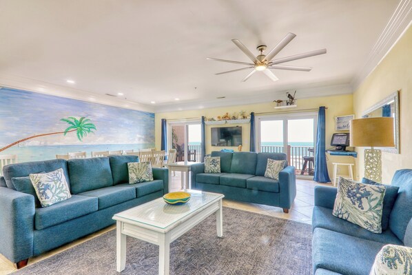 A living room with two blue sofas, a white coffee table, and a ceiling fan.