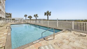 A rectangular pool with a 3 FT depth marker, surrounded by a white fence and palm trees, with a view of the ocean and a building in the background. - Atlantis Villas 202 by Elliott Beach Rentals (NORTH MYRTLE BEACH)