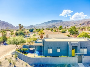 A modern building with a pool, surrounded by mountains and palm trees.