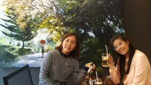 Two people sitting at a table with drinks, in front of a large painting of a forest scene. - Jaidee Cafe & Hostel Chiangrai (Chiang Rai)