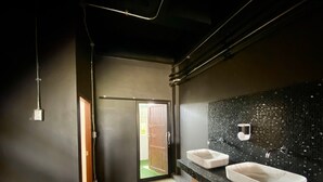 A modern bathroom with two sinks, a black tiled backsplash, and a door leading to another room. - Jaidee Cafe & Hostel Chiangrai (Chiang Rai)