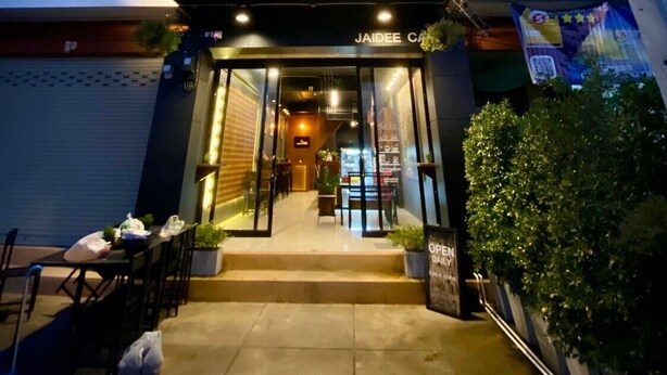 A modern building with a glass entrance, a visible outdoor seating area, and signage for 'Tasaki' and 'DAIKIN'. - Jaidee Cafe & Hostel Chiangrai (Chiang Rai)