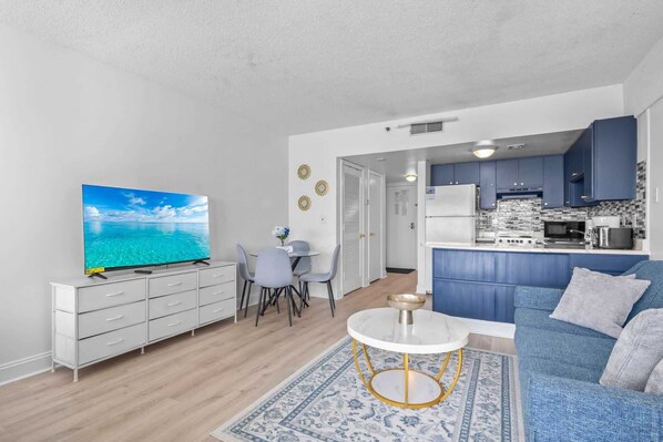 Un espacio habitable compacto con comedor, cocina, sofá y televisor.