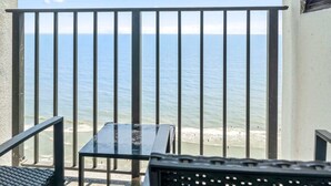 Un balcón con vista al mar, una mesa y una silla.