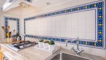 Een koelkast, een oven, een waterkoker, kookgerei, borden en bestek