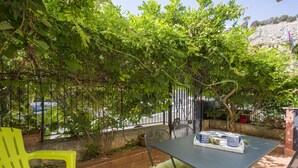 A patio with a table and chairs, surrounded by greenery and a view of a street. - La Casa di Sara a Mondello by Wonderful Italy (Palermo)