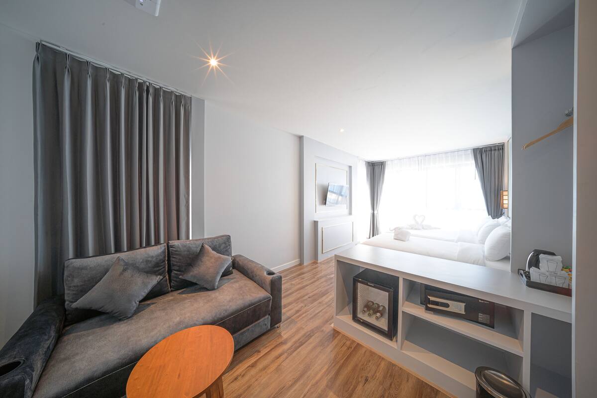A modern living room with a sofa, a coffee table, and a TV area with a white sofa and a coffee machine.