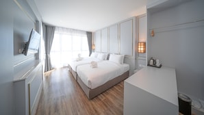 Ein Hotelzimmer mit zwei Betten, einem Schreibtisch, einem Fernseher und einem Fenster mit Vorhängen.