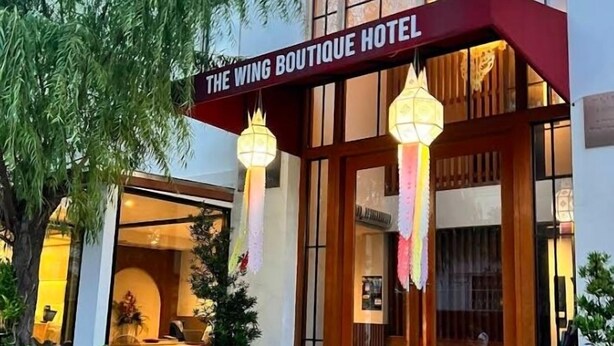Eingang des Wing Boutique Hotels mit Schild, Holztüren und hängenden Laternen.
