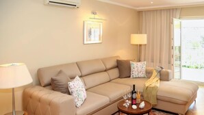 Una sala moderna con un sofá color beige, una mesa de centro redonda y una alfombra estampada.