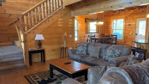 A wooden interior with a staircase, a sofa set, and a coffee table.
