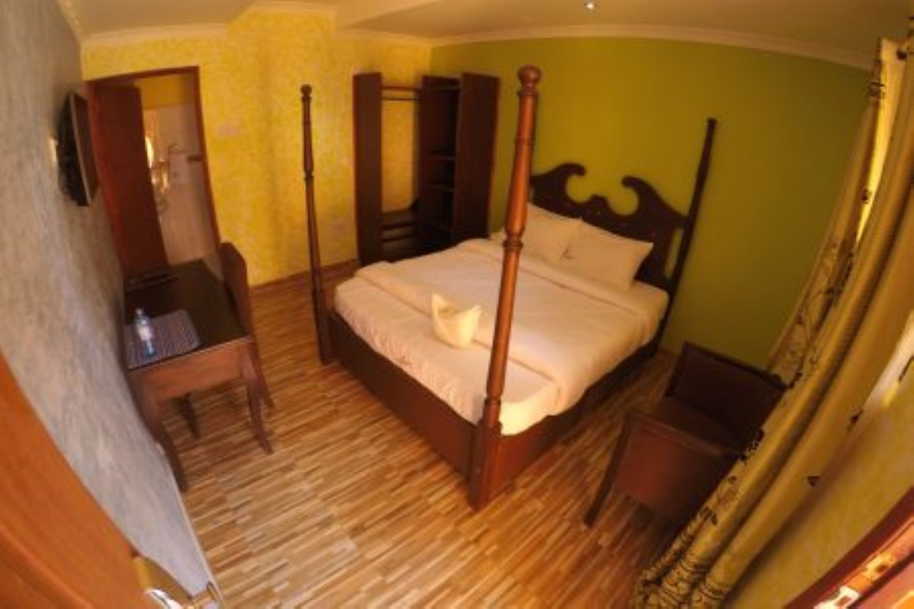 A four-poster bed with a wooden frame, a bedside table, and a nightstand.