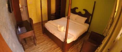 A four-poster bed with a wooden frame, a bedside table, and a nightstand.