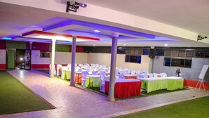 A banquet hall with rows of tables, chairs, and a stage area.