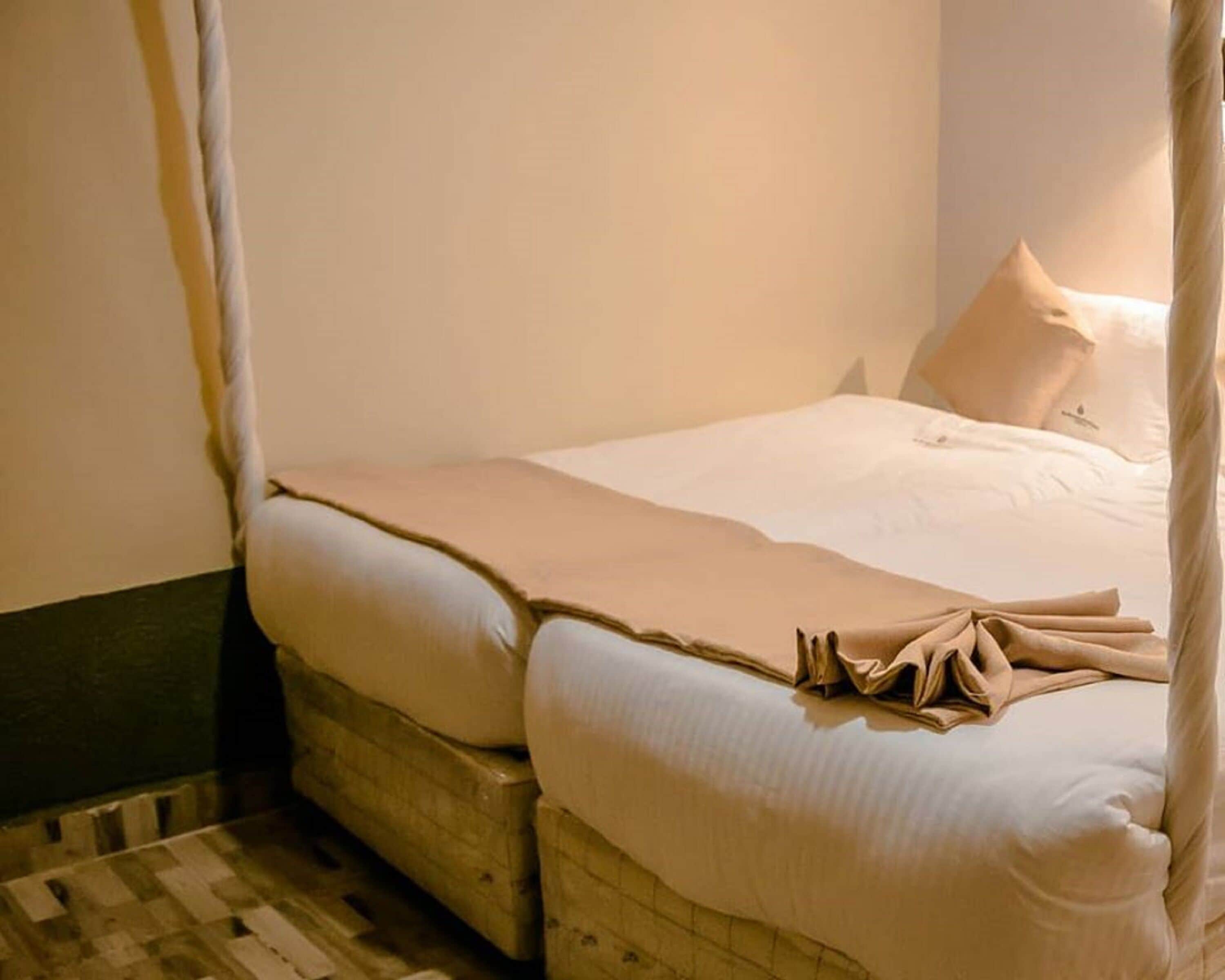 Uma cama de solteiro com dossel, roupa de cama branca e cabeceira de madeira.