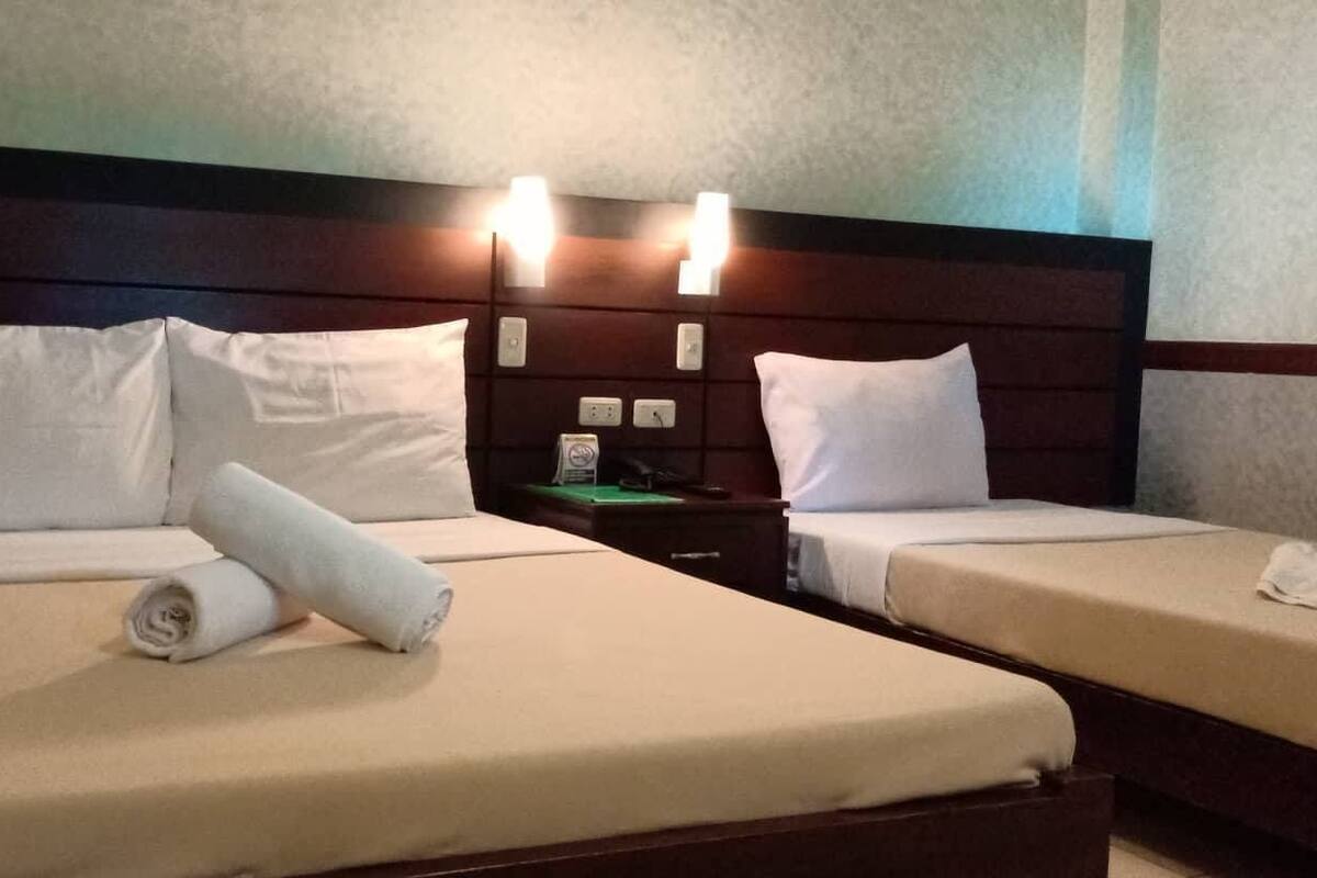 Hotellihuone, jossa on kaksi sänkyä. Jokaisessa sängyssä on valkoiset lakanat ja tyynyt, puinen pääty sekä yöpöytävalaisimet.