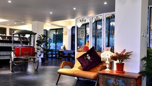 A modern lobby with a leather sofa, decorative panels, a vintage cart, and a view of the outdoors. - Sunlight Gallery landscape B&B (Chenggong)