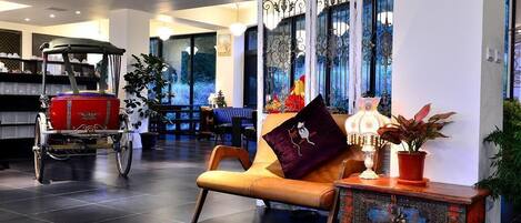 A modern lobby with a leather sofa, decorative panels, a vintage cart, and a view of the outdoors.