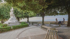 Un parc agrémenté d’une statue, de bancs et d’une zone dallée offrant une vue sur le paysage.