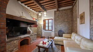 Un salon chaleureux avec une cheminée, un canapé et un mur en pierre.
