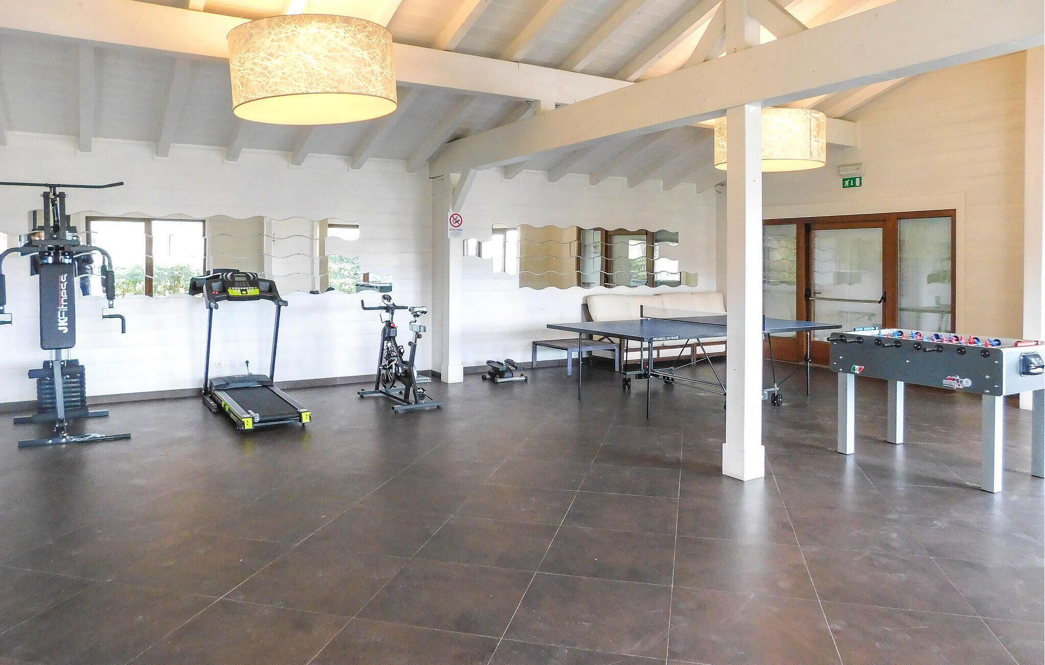 A spacious indoor area with exercise equipment, a foosball table, and a ping pong table.