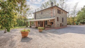 Une maison en pierre dotée d’un patio couvert, de meubles d’extérieur et de plantes en pot.