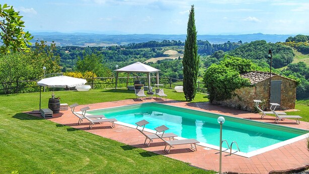 Une piscine avec des chaises longues, un belvédère et une vue sur la campagne.