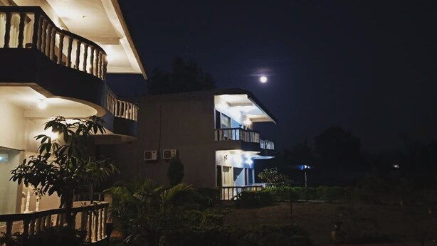 A multi-story building with balconies, a staircase, and a crescent moon in the sky.