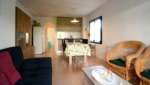 Ein Wohnzimmer mit einer Couch, einem Esstisch mit Stühlen und Korbmöbeln.