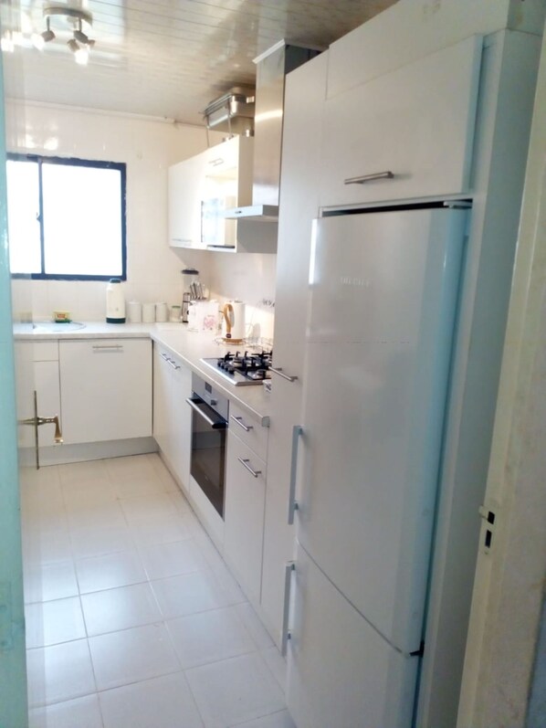 Apartamento, 3 quartos | Cozinha privada | Geladeira grande, micro-ondas, fogão, cooktop