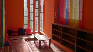 A room with orange walls, a large window with stained glass, a wooden bench, a small table, and a bookshelf. - Exotic wind sand city 86 (Taitung)
