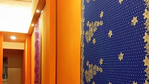 A hallway with wooden flooring, orange walls, and blue patterned wallpaper with gold floral designs. - Exotic wind sand city 86 (Taitung)