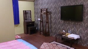 A hotel room with a bed, a TV, a wardrobe, a mirror, a desk with a chair, and a patterned wall. - Exotic wind sand city 86 (Taitung)