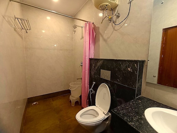 A bathroom with a toilet, a sink, and a shower area. - Hotel Ganga Azure (Haridwar)