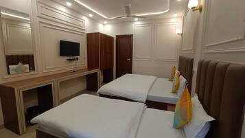 Een hotelkamer met twee bedden, een bureau, een televisie en een plafondventilator.