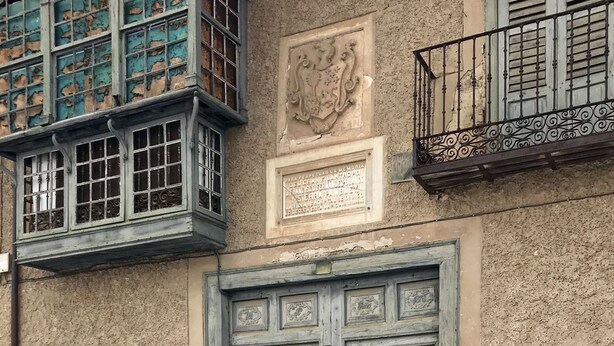 Ein Gebäude mit zwei großen Holztüren und einem Fenster mit dekorativen Metallgitterstäben.
