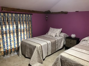 A bedroom with a bed, a nightstand, and a window with curtains. - B&B Puente de Órbigo (Hospital de Orbigo)