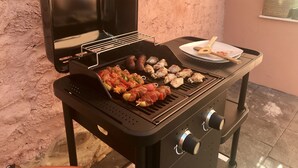 Ein tragbarer Grill mit verschiedenen Fleisch- und Gemüsesorten, die zubereitet werden.