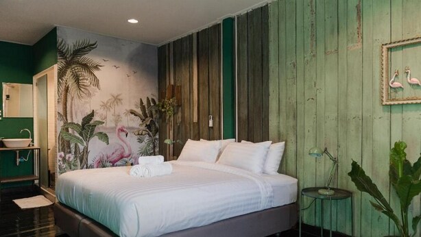 A bedroom with a bed, a nightstand, a wall-mounted lamp, and a mirror. - Tang House (Bangkok)
