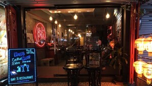 A bar and restaurant with a neon sign, tables, and a patterned floor. - Tang House (Bangkok)