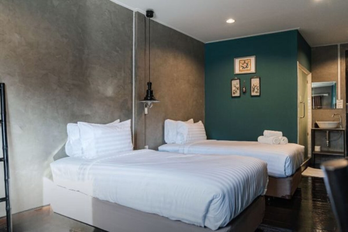 Habitació d'hotel amb dos llits, un bany i una petita zona de seients.